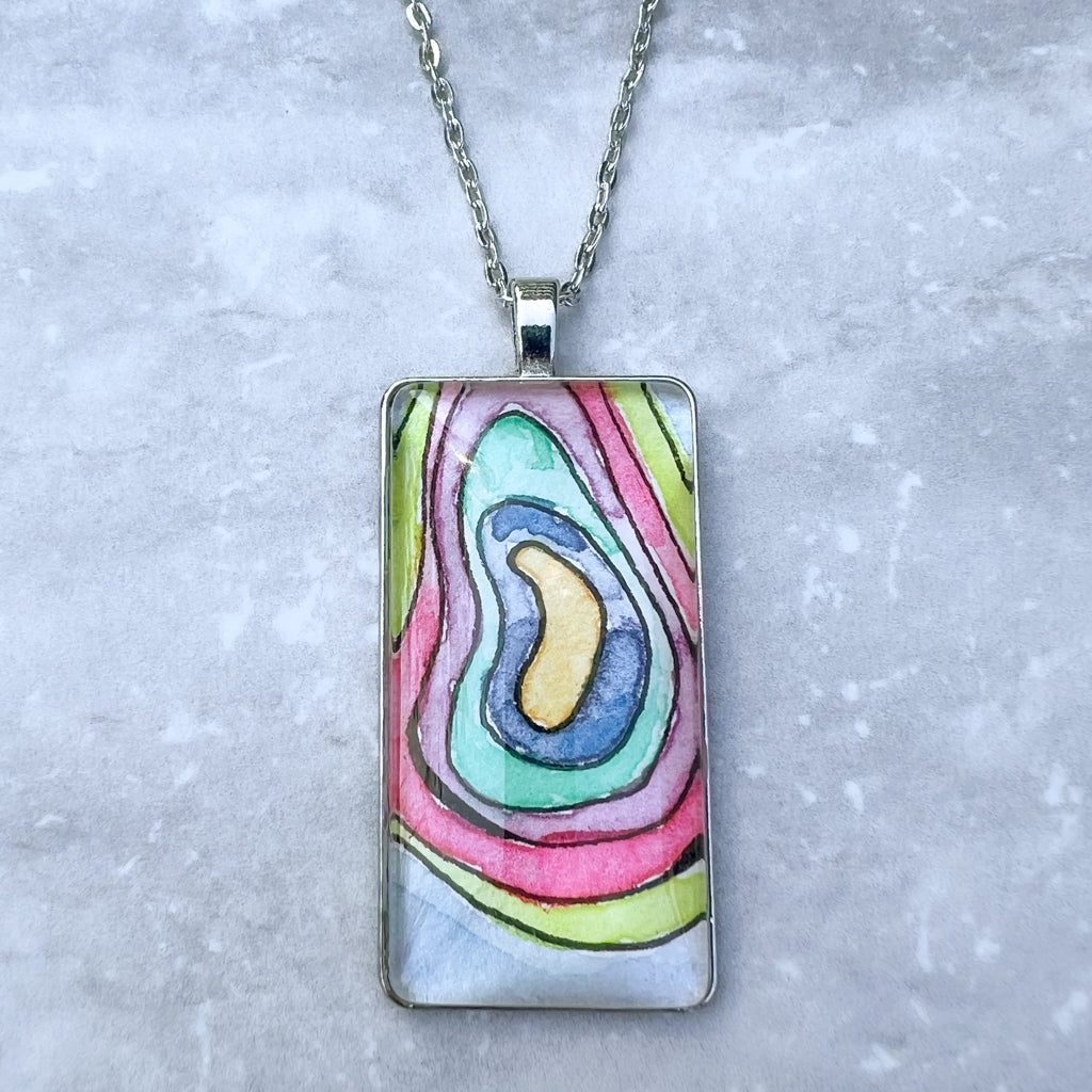 Hand-painted watercolor pendant with concentric rings of bright colors on a pale blue background. 