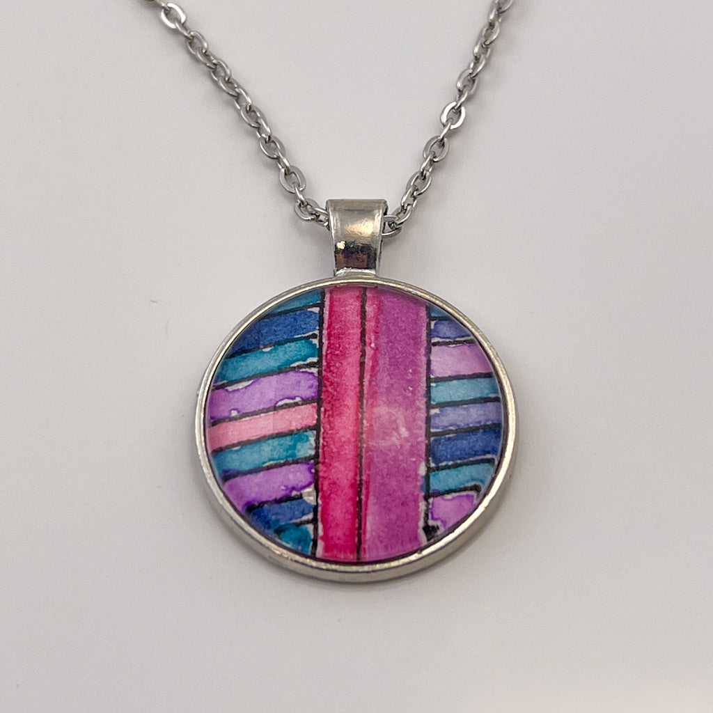 hand-painted watercolor pendant featuring blue, purple and teal stripes bisected with larger pink stripes. 