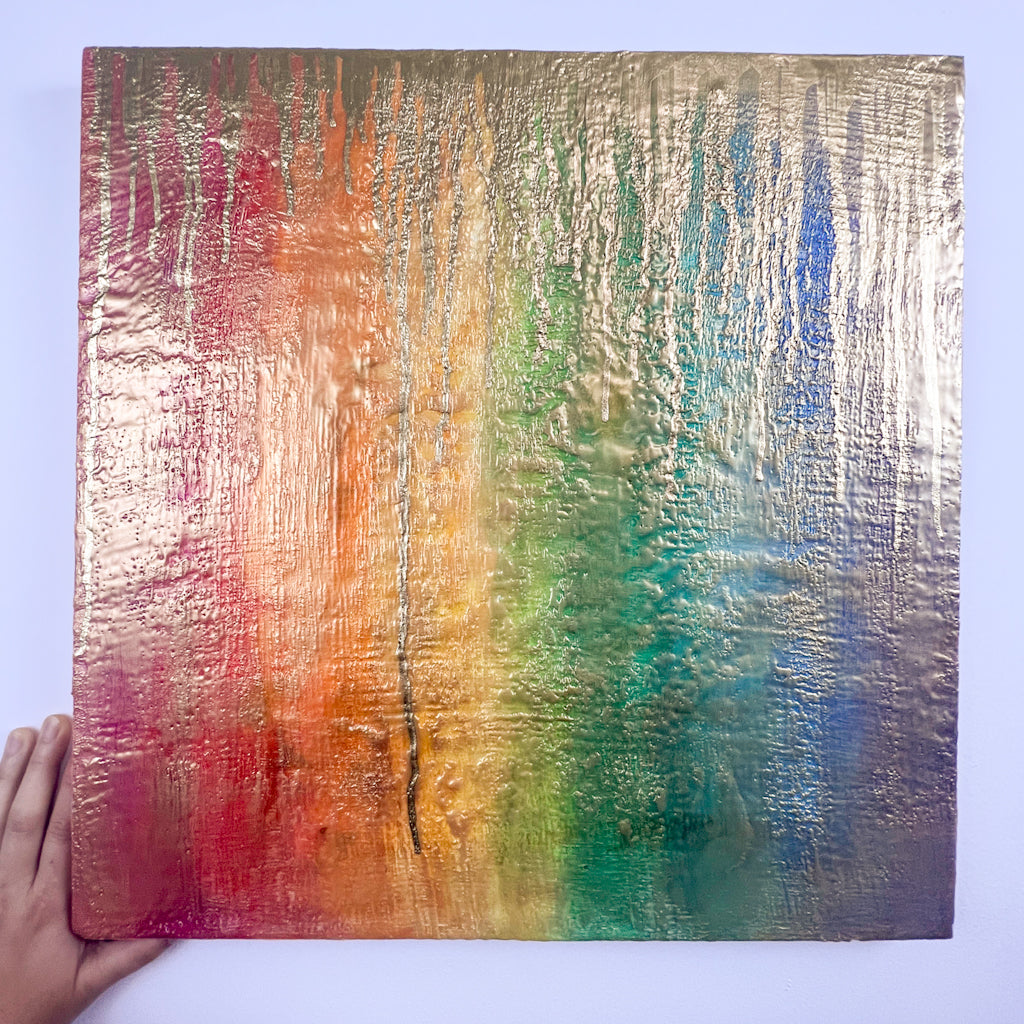 Rainbow-huedencaustic painting, lightly gilded with gold sheen, with drips of deeper gold raining down from the top edge of the work. 