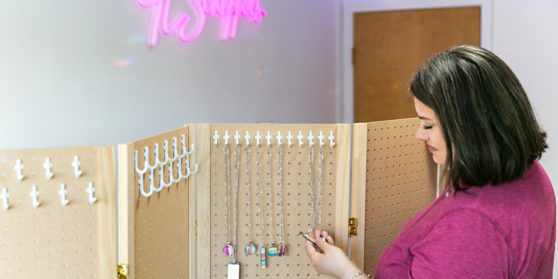 Jamie Scheppers in her home office taking inventory of hand-painted watercolor necklaces. 