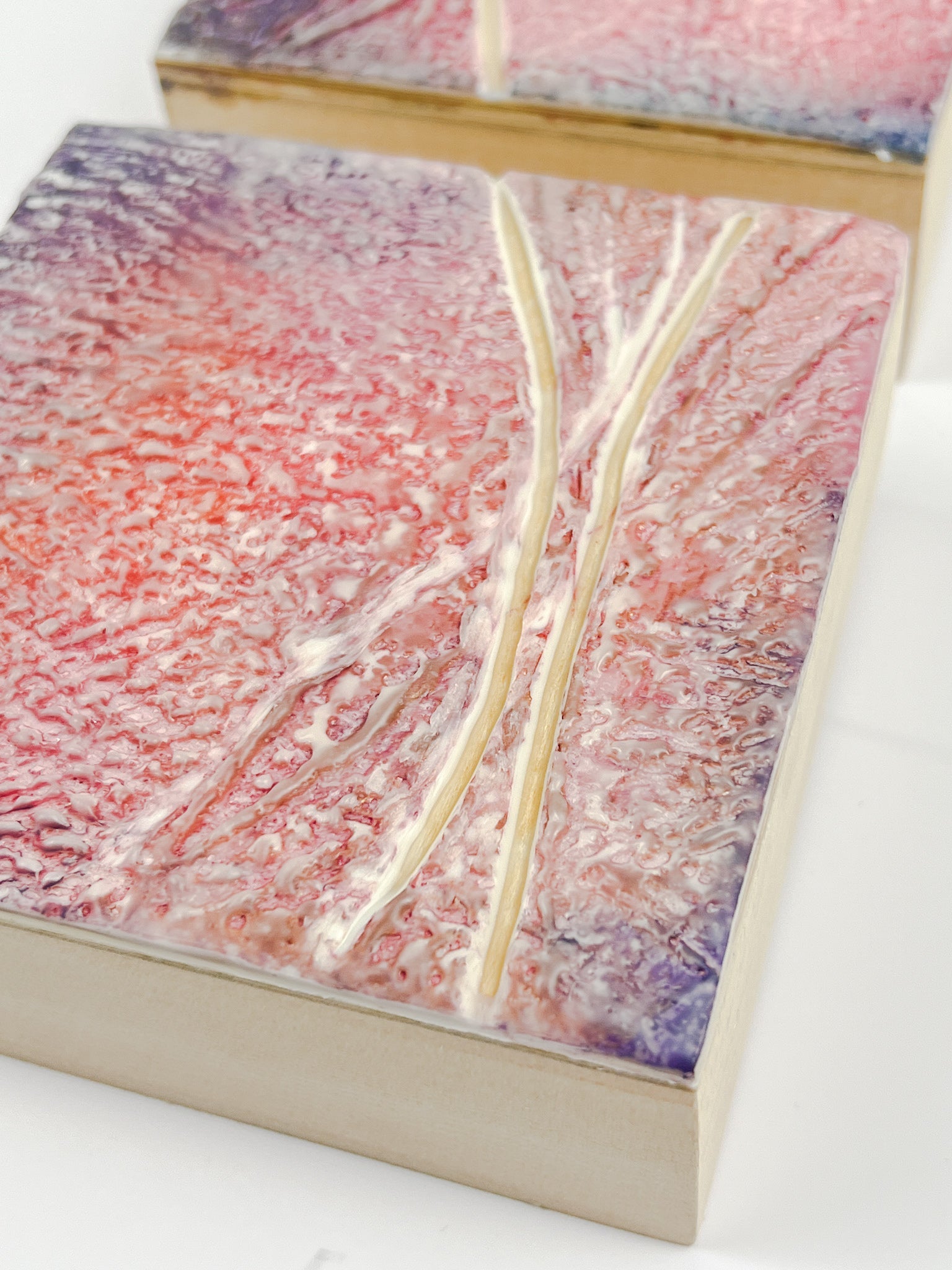 Two pink and purple textured encaustic paintings measuring 4" x 4" 