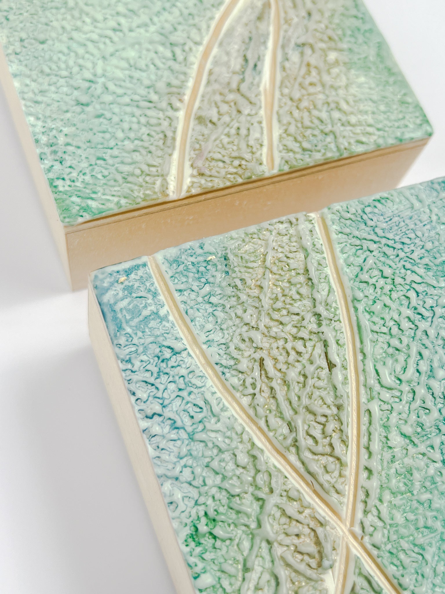 Two light seafoam-colored textured encaustic paintings. Each is 4" by 4."