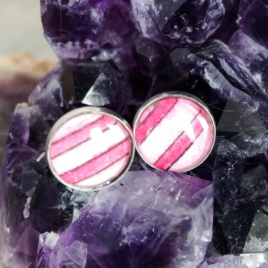 Purple and lavender stripe stud earrings displayed on a large amethyst. 
