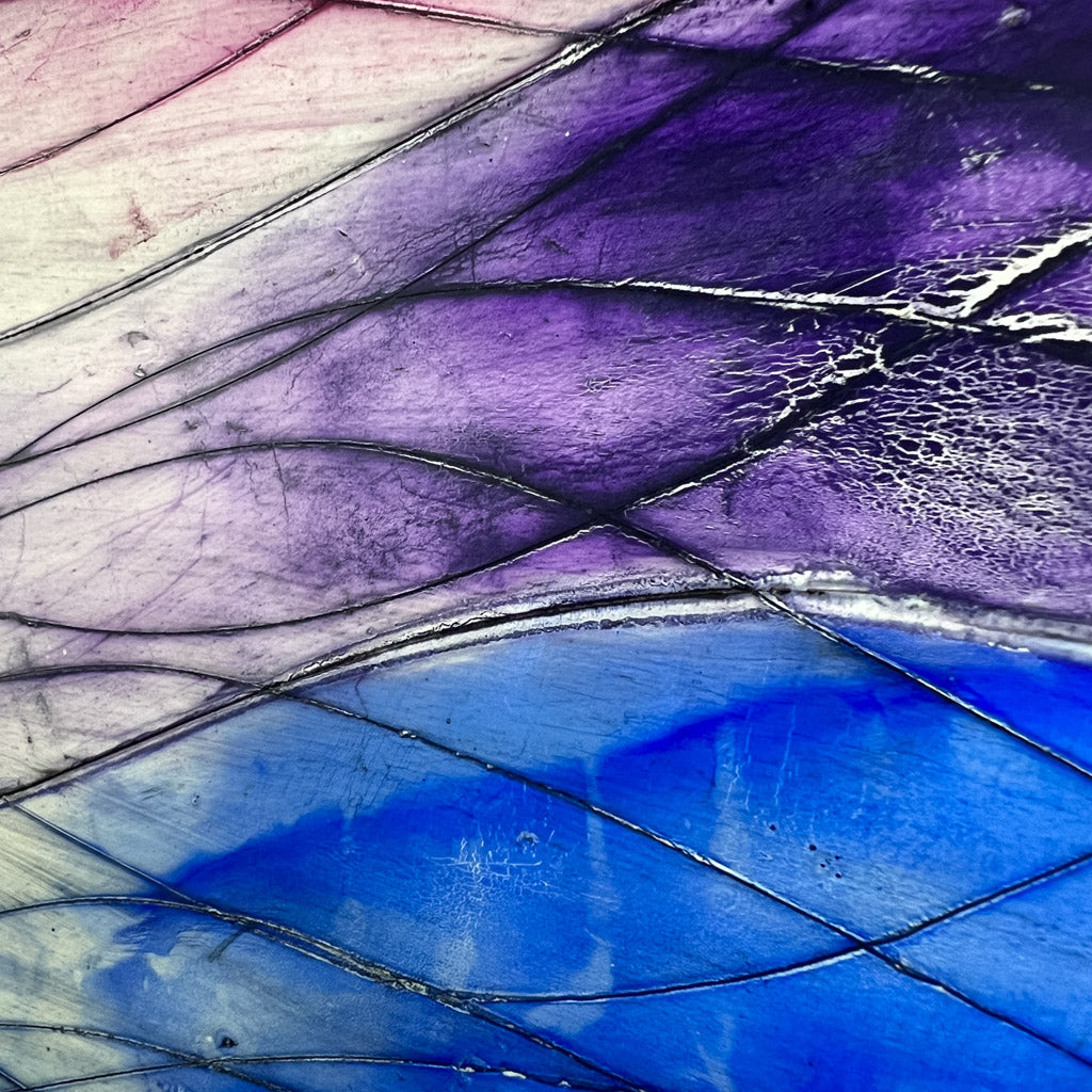 Encaustic painting, featuring a rainbow of waves that have been faded away, dirtied by black oil paint, and carved into with additional wavy lines. 