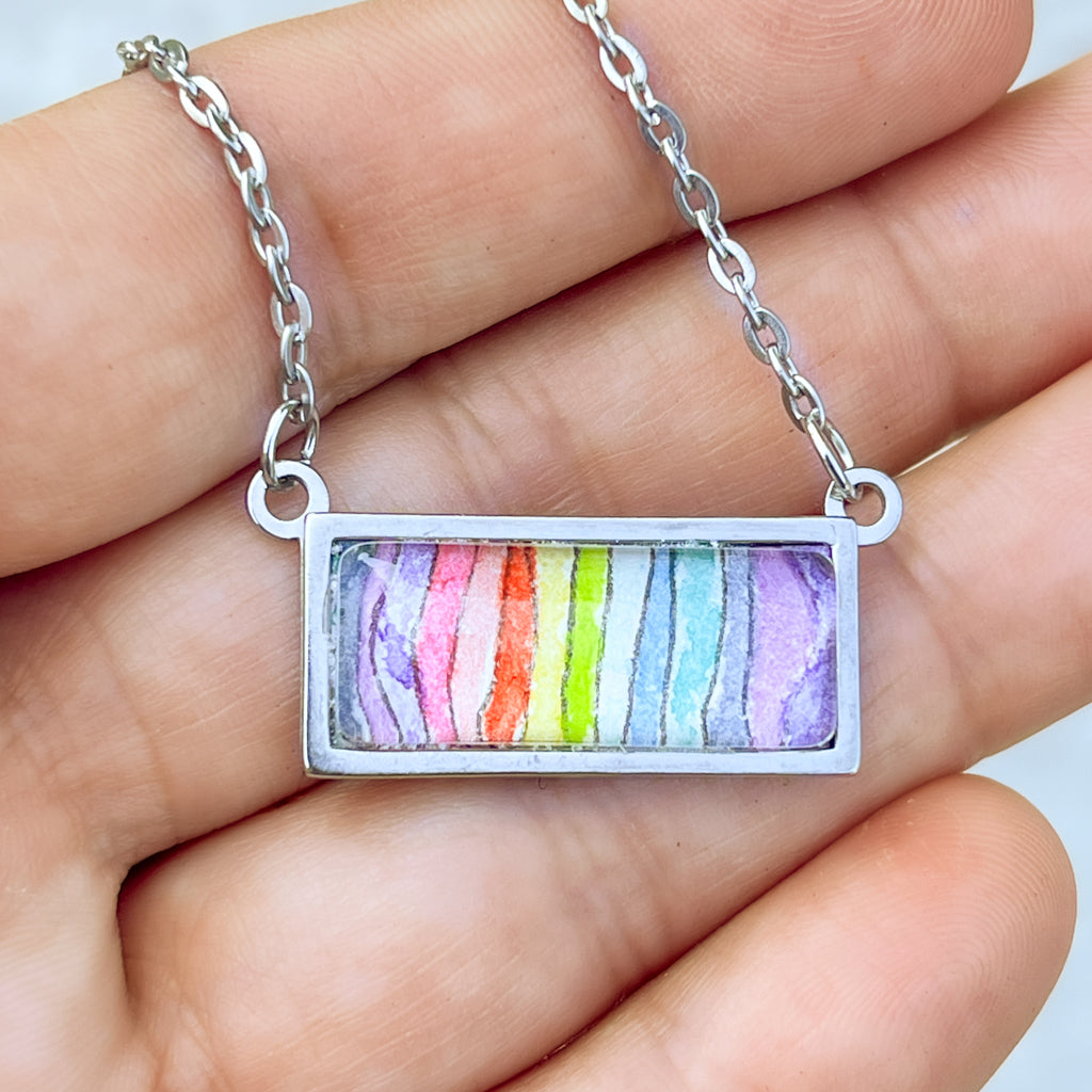 Spectrum necklace featuring a rainbow of wavy stripes in watercolor and ink. . 
