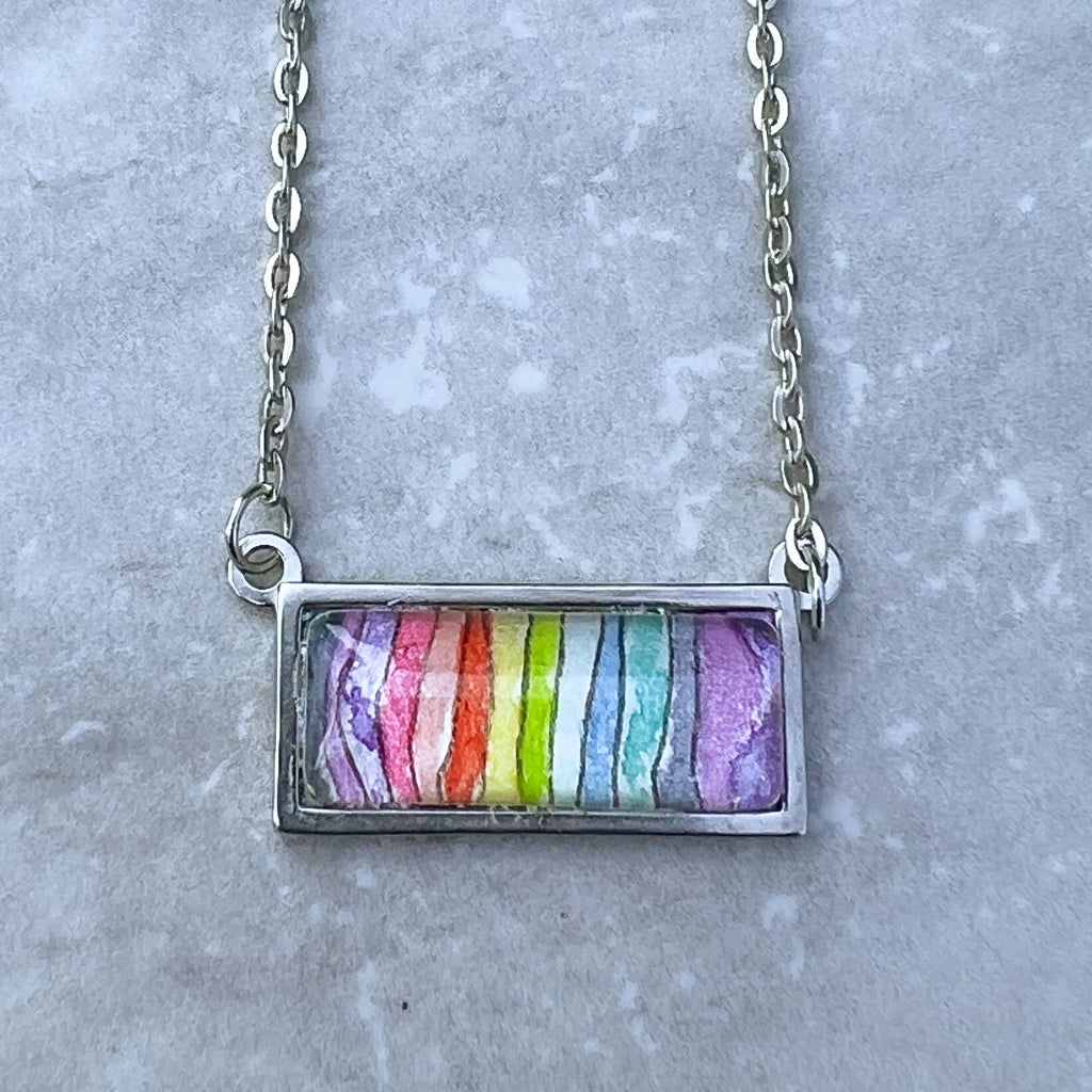 Spectrum necklace featuring a rainbow of wavy stripes in watercolor and ink. . 