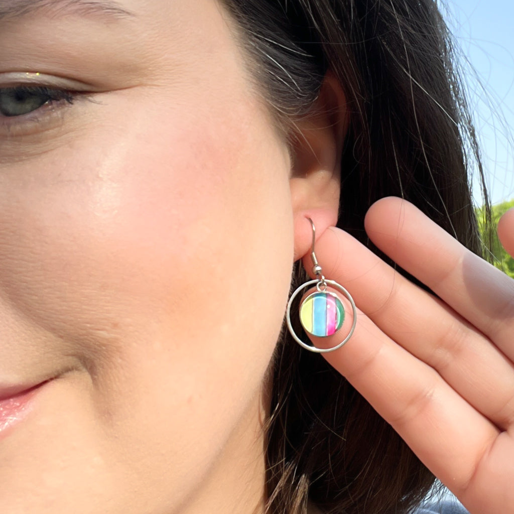 Multi-colored watercolor earrings with bright colors and a round frame. 