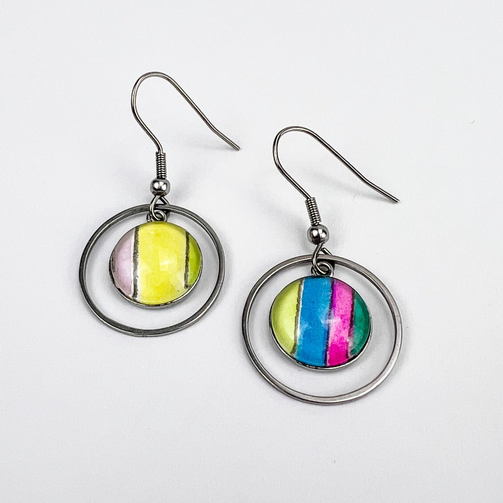 Half-inch circles of watercolor art protected behind glass cabochons in stainless steel settings. Surrounded by circular frames and displayed on a white background. 