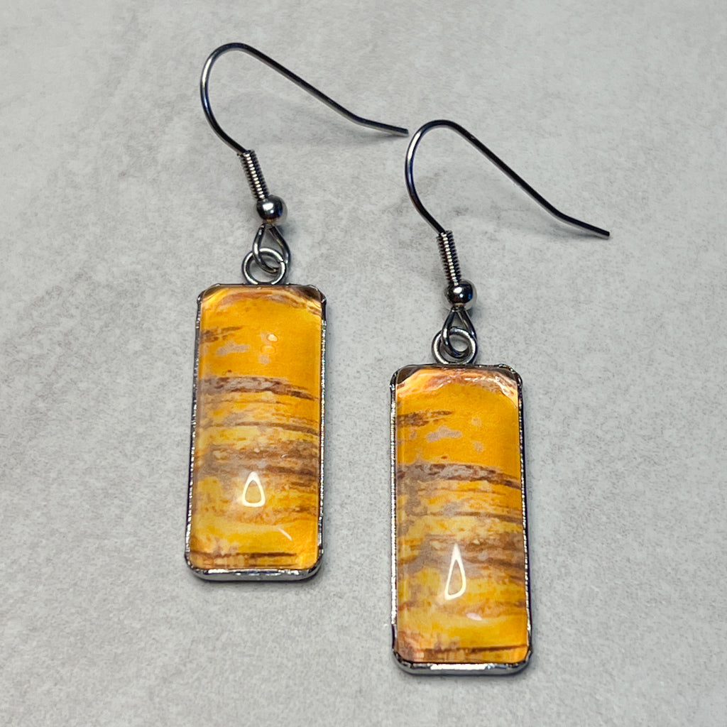 Rectangular drop earrings featuring orange watercolor art under glass cabochons.