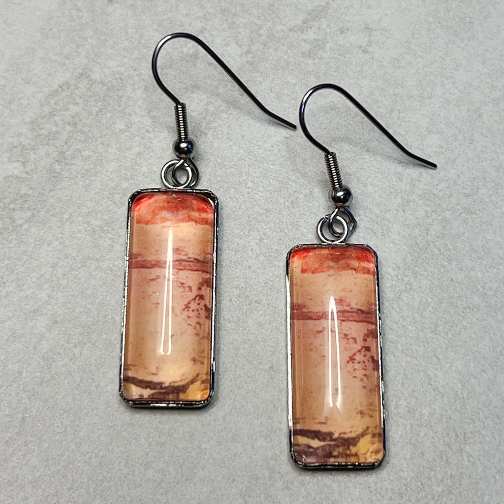 Rectangular drop earrings featuring peach watercolor art under glass cabochons.