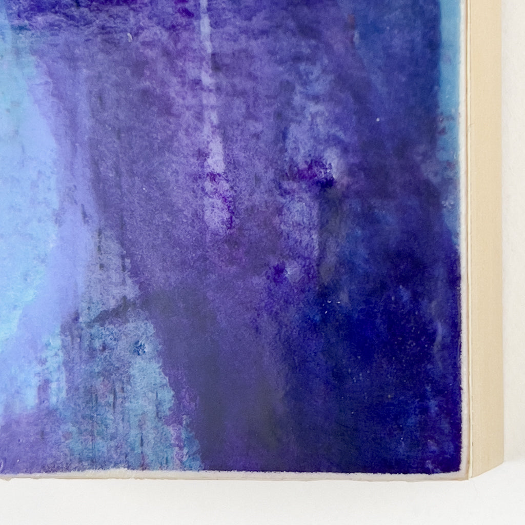 Front view of watercolor and encaustic painting, featuring layered shades of blue, purple and teal. 