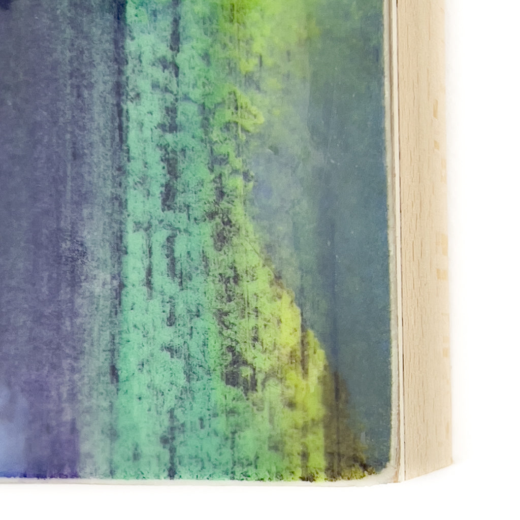 Front view of watercolor and encaustic painting, featuring layered shades of blue, purple and green.