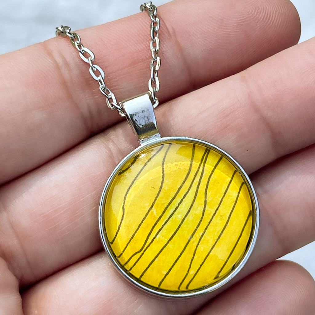 Detail of Tiger Stripe watercolor pendant shown in hand for scale.