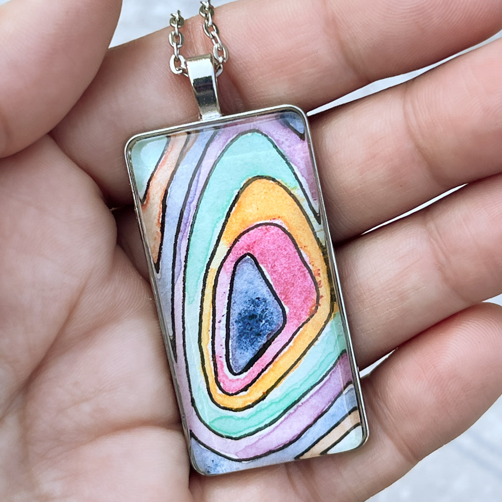 Topo pendant shown held in a hand for scale. 