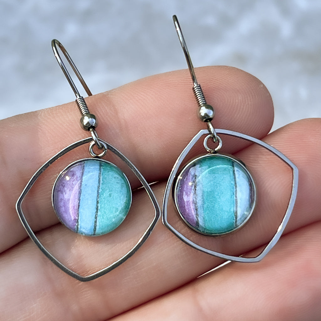 Water Iris watercolor earrings shown in hand. 